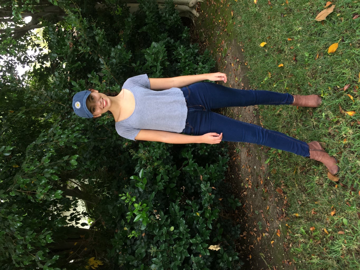 Girl in baseball cap, grey shirt, jeans, and brown boots