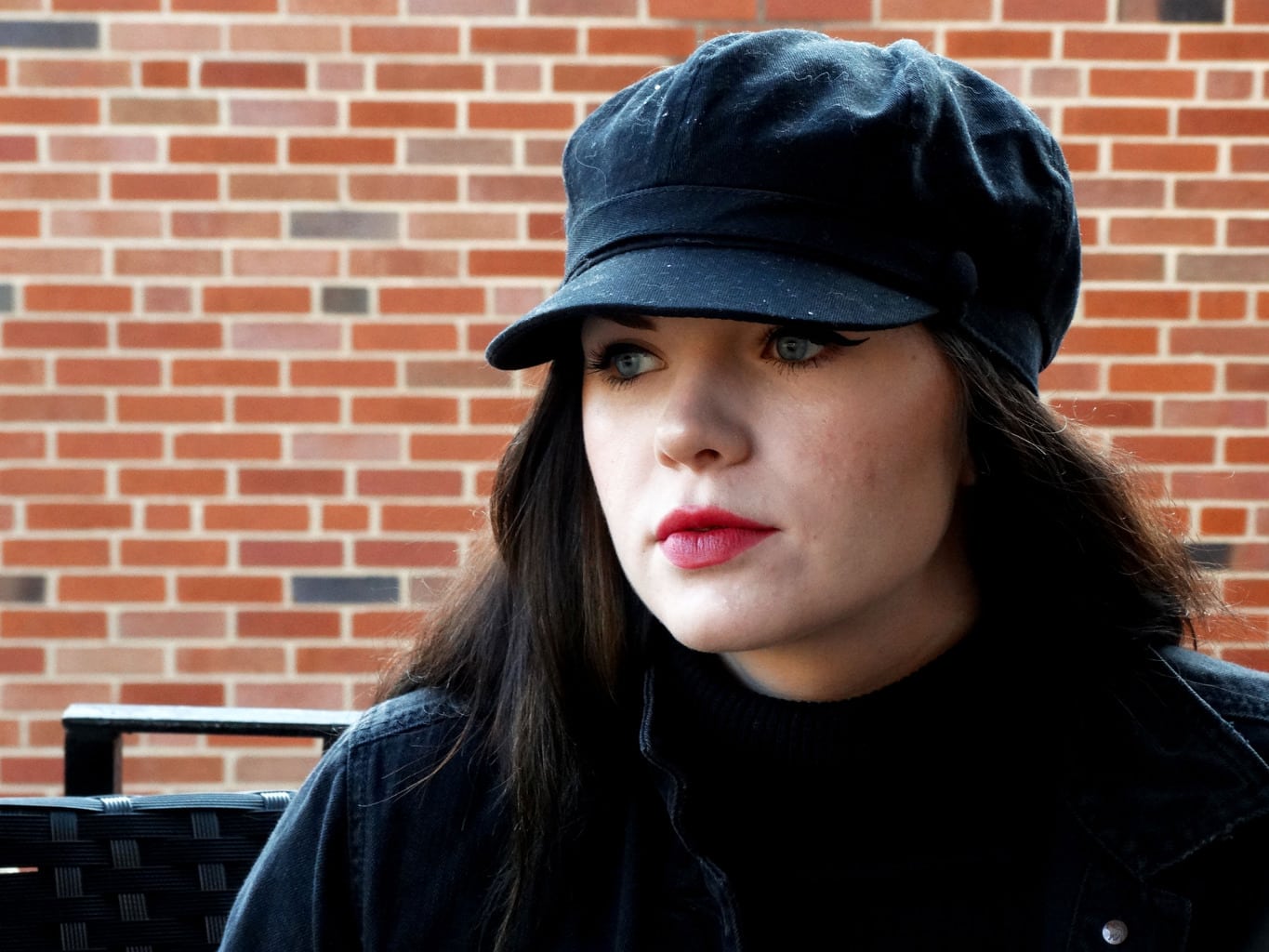 Mackenzie wears a black cabby hat with dramatic cat eyeliner and a bold pink lip.