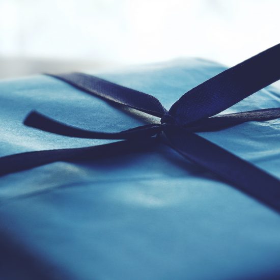 Close-up photo of blue wrapped gift with navy blue ribbon