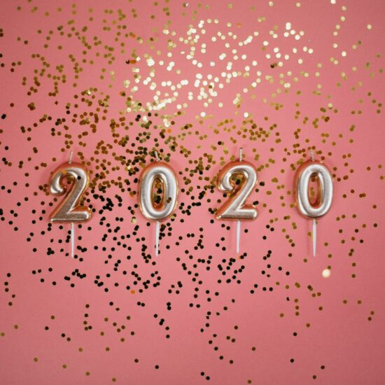 2020 pale gold number candles and gold sparkles against a coral-pink background